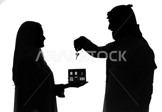 اسكان وتمليك، ايماءات تعبر عن السعادة بشراء عقار جديد, بورتريه صورة ظلية لرجل عربي خليجي سعودي يحمل مفتاح البيت الجديد ويفاجئ زوجته، زوجة سعودية تحمل مجسم بيت صغير, امتلاك سكن حديث والاستقرار العائلي، خلفية بيضاء, سيلوليت