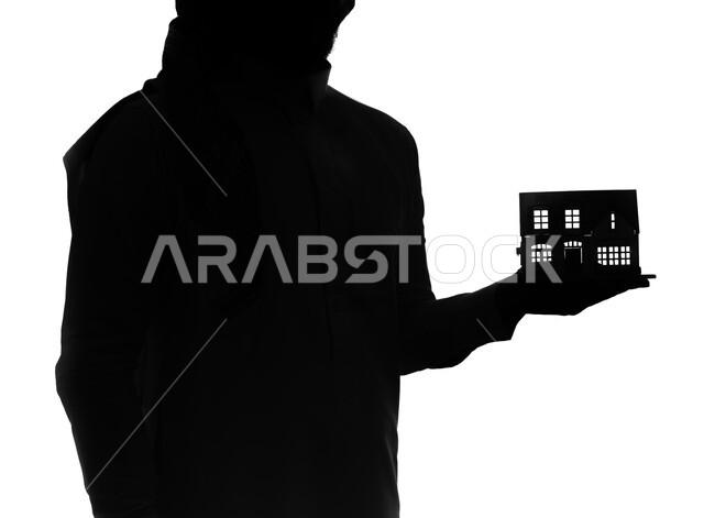 Buying new housing and family stability, owning a new property, a silhouette portrait of a Saudi Arabian Gulf man carrying a model of a small house, housing and ownership, white background, cellulite