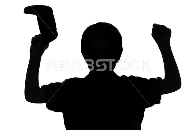 Practicing entertaining recreational activities, having fun and having fun with video games and entertainment PlayStation, a silhouette portrait of a Saudi Arabian Gulf child holding a joystick in his hand and playing video games, with gestures and expres