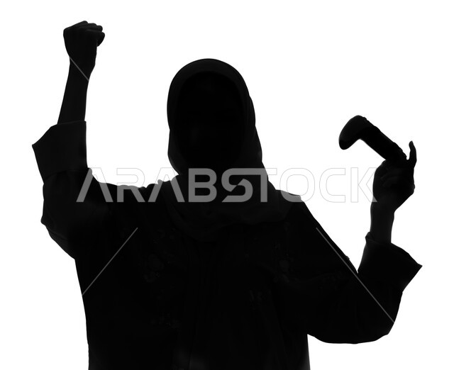إيماءات و تعابير تدل على الفوز و الانتصار، المتعة والمرح بألعاب الفيديو والبلايستيشن الترفيهية , بورتريه صورة ظلية لإمرأة عربية خليجية سعودية تمسك بيدها عصا التحكم و تلعب بألعاب الفيديو، ممارسة أنشطة ترفيهية مسلية, خلفية بيضاء, سيلوليت