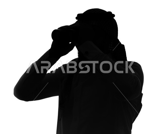 التخطيط المستقبلي للأهداف والطموحات ، بورتريه صورة ظلية لرجل عربي خليجي سعودي يرتدي الزي السعودي التقليدي ينظر من خلال المنظار ثنائي العينين، حب الاستكشاف والمغامرة ، رؤية مستقبلية لدى الراشدين، رؤية الأشياء البعيدة, خلفية بيضاء, سيلوليت