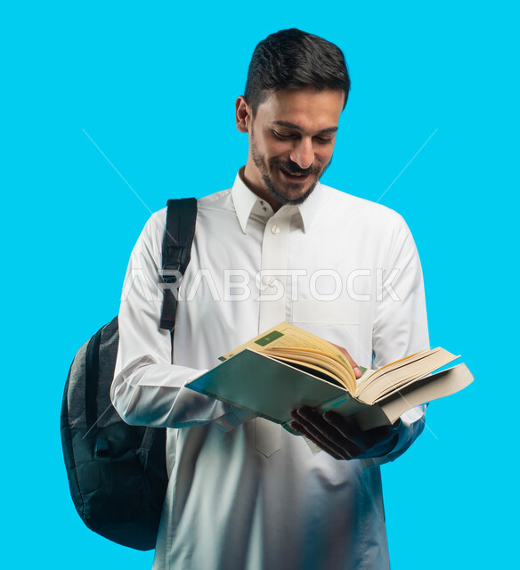 تدوين الملاحظات وحل الواجبات اليومية ، بورتريه لطالب جامعي يرتدي الزي العربي الخليجي السعودي يحمل بيده كتب  ، قراءة الكتب وإكتساب المعرفة ، التعليم في المملكة العربية السعودية ، التحضير ومراجعة البحوث العلمية ، مفهوم التثقف والتثقيف ، خلفية زرقاء