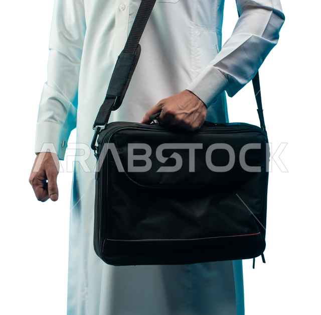 Getting ready to go to work, a portrait of a Saudi Arabian Gulf businessman wearing Saudi dress carrying a laptop bag on his shoulder A Saudi Arab university