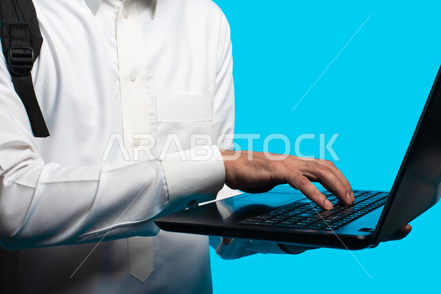 Distance learning, preparation for electronic university lectures, the use of modern technical devices, a portrait of an Arab university student wearing the Saudi Gulf uniform making a video call through a laptop, reviewing daily lessons, education in the