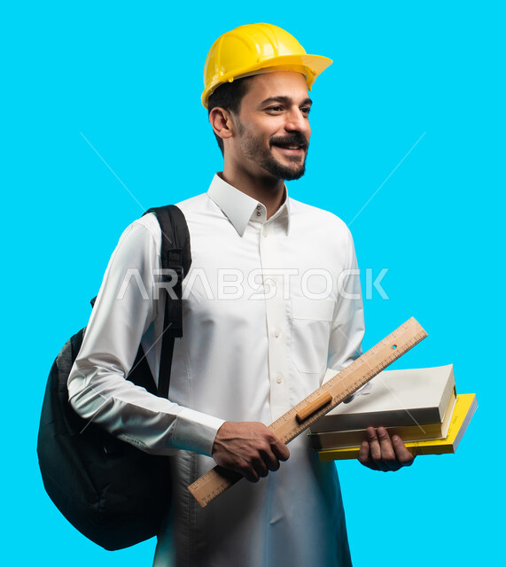 التعليم في المملكة العربية السعودية ، إيماءات وجه تدل على الفرح والنجاح ، بورتريه طالب جامعي يرتدي الزي الخليجي السعودي يحمل بيده كتب ومعدات الهندسة ، تدوين الملاحظات وكتابة تقارير وأبحاث علمية ، إدارة المشاريع الهندسية ، مهن ووظائف هندسية ، خلفية زرقاء