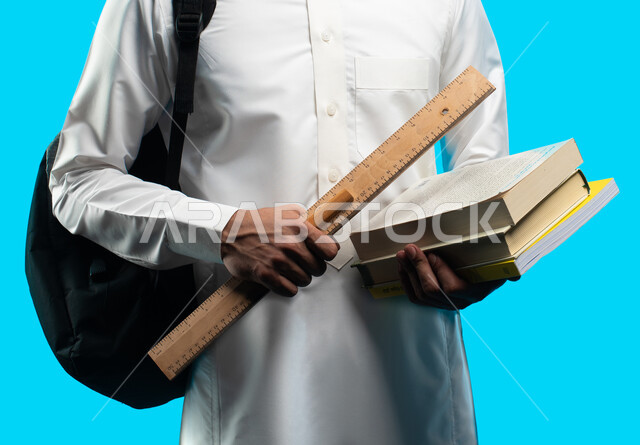 بورتريه طالب جامعي  يرتدي الزي الخليجي السعودي يحمل بيده كتب ومعدات الهندسة ، تدوين الملاحظات وكتابة تقارير وأبحاث علمية ، إدارة المشاريع الهندسية ، التعليم في المملكة العربية السعودية ، مهن ووظائف هندسية ، خلفية زرقاء