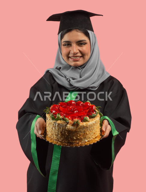A female graduate holding a cake mold decorated with fruits, a portrait of a Saudi Arabian Gulf university student wearing an abaya and a graduation cap, a happy festive atmosphere, success, excellence and graduation from the university, education in the 