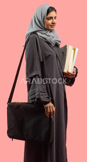 الاستعداد للعام الدراسي الجامعي الجديد، بورتريه لطالبة جامعية عربية سعودية خليجية تحمل الكتب وحقيبة اللابتوب، قراءة الكتب ومراجعة الدروس اليومية، التعليم في المملكة العربية السعودية، خلفية وردية