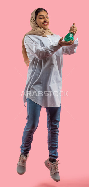  التطيب والتعطر بالزيوت العطريه الطبيعيه, بورتريه لفتاه عربيه خليجية سعودية تقوم بوضع عطر نسائي, التسويق لمنتجات العطور النسائيه المتميزه, الاهتمام بالجمال والاناقه والمظهر الخارجي, خلفيه ورديه, صورة الجسم بالطول الكامل