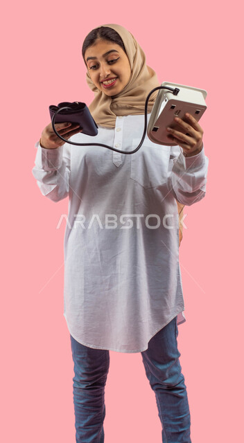  التسوق والشراء من محلات ومتاجر القطاع الطبي والصحي, جهاز قياس ضغط الدم الالكتروني, بورتريه لشابه عربيه سعوديه خليجيه تستخدم جهاز الضغط , التسويق للأجهزه والأدوات الطبيه الحديثه, خلفيه ورديه. 