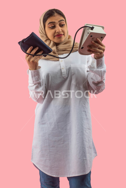 جهاز قياس ضغط الدم الالكتروني, بورتريه لشابه عربيه سعوديه خليجيه تستخدم جهاز الضغط , التسويق للأجهزه والأدوات الطبيه الحديثه, التسوق والشراء من محلات ومتاجر القطاع الطبي والصحي, خلفيه ورديه. 