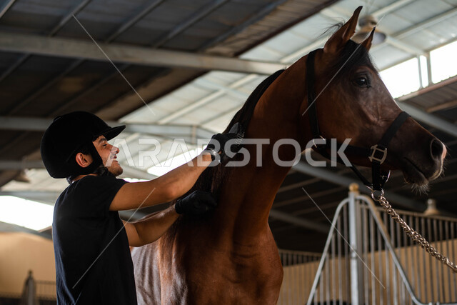 قضاء وقت ممتع مع جواد بني أصيل في مزرعة تربية وتدريب الجياد في المملكة العربية السعودية ، فارس عربي سعودي خليجي يرتدي زي الفروسية ويقوم بتمشيط شعر الفرس والاعتناء به، ممارسة هواية ركوب الخيل ، مهارات وأنشطة ترفيهية في نادي الفروسية 