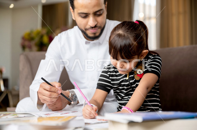 تلميذة سعودية خليجية تدرس في المنزل مع والدها ، يساعدها على تأدية واجباتها المدرسية ، التعلم عن بعد ، مفهوم التعليم عبر الانترنت ، التعليم المنزلي اثناء الحجر الصحي و تفشي فيروس كورونا ، العزلة الذاتية .