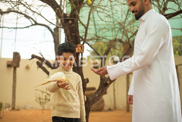 Breeding and training birds in the nature reserve, spending fun times in the zoo in the Kingdom of Saudi Arabia, a Saudi Arabian Gulf man accompanied by his son, recreational activities with birds.