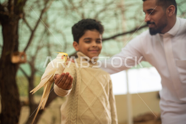 رعاية وتربية الطيور في المحمية الطبيعية، أنشطة ترفيهية في فعالية سفاري موسم الرياض، رجل عربي خليجي سعودي وابنه يقضيان أوقات ممتعة مع الطيور في حديقة الحيوانات في المملكة العربية السعودية .