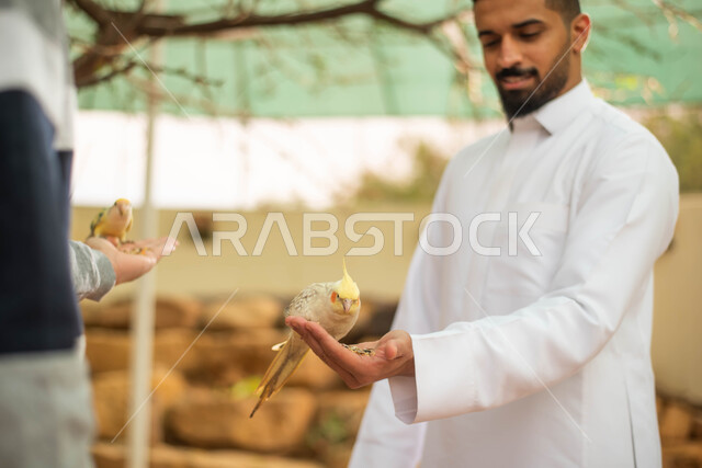 فعاليات ترفيهية في موسم سفاري الرياض، تربية ورعاية الحيوانات، ايماءات وجه تدل على الاستمتاع مع الصديق، صورة مقربة لرجلين عربيين خليجيين سعوديين يقضيان أوقات مسلية مع الطيور في محمية طبيعية في المملكة العربية السعودية.