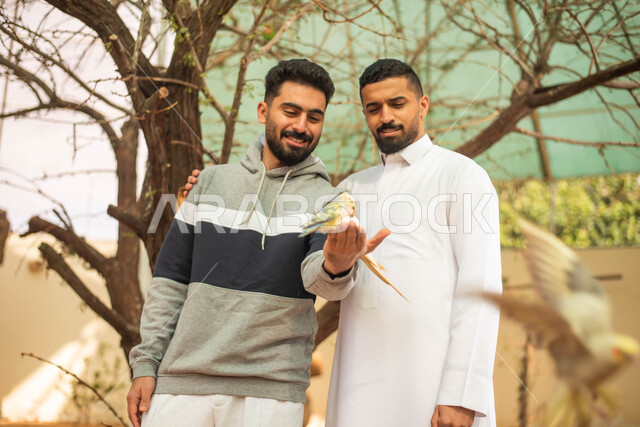 تربية ورعاية الحيوانات، ايماءات وجه تدل على الاستمتاع مع الصديق، فعالية سفاري موسم الرياض، رجلان عربيان خليجيان سعوديان يقضيان أوقات مسلية مع الطيور في محمية طبيعية في المملكة العربية السعودية.