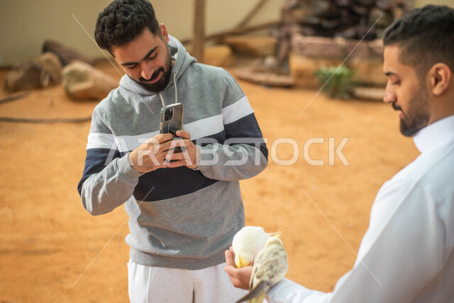 مزارع تربية الطيور، التقاط  صور تذكارية ، رجلان عربيان خليجيان سعوديان في محمية طبيعية في المملكة العربية السعودية، استخدام الهاتف المحمول ، أنشطة ترفيهية وأماكن سياحية ، فعالية سفاري موسم الرياض.