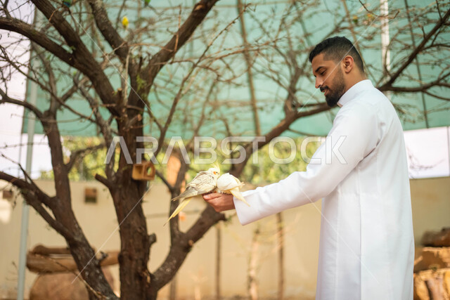 ايماءات تدل على السعاده اثناء اطعام الطيور ، حيوانات برية في المحمية الطبيعية،  شاب عربي خليجي سعودي في حديقة الحيوانات في المملكة العربية السعودية، فعالية سفاري موسم الرياض