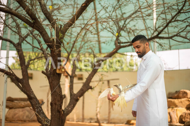 ايماءات تدل على السعاده اثناء اطعام الطيور ، حيوانات برية في المحمية الطبيعية،  شاب عربي خليجي سعودي في حديقة الحيوانات في المملكة العربية السعودية، فعالية سفاري موسم الرياض