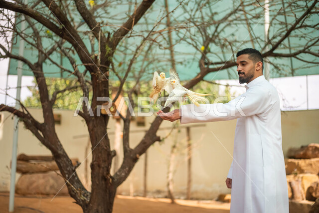 حيوانات برية في المحمية الطبيعية، أنشطة وفعاليات ترفيهية في موسم سفاري الرياض، رجل عربي سعودي خليجي يرتدي الثوب السعودي التقليدي و يقضي أوقات ممتعة في حديقة الحيوانات في المملكة العربية السعودية.