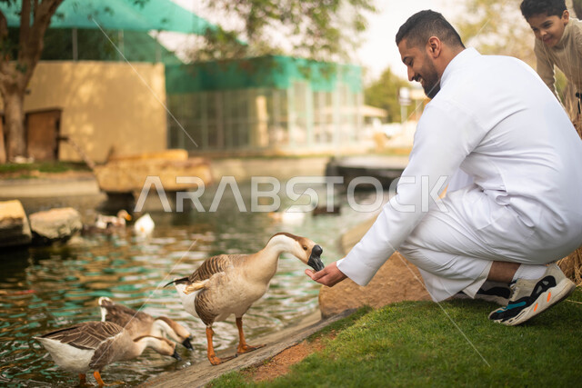 ايماءات تدل على السعاده اثناء اطعام الطيور ، حيوانات برية في المحمية الطبيعية،  شاب عربي خليجي سعودي في حديقة الحيوانات في المملكة العربية السعودية، فعالية سفاري موسم الرياض