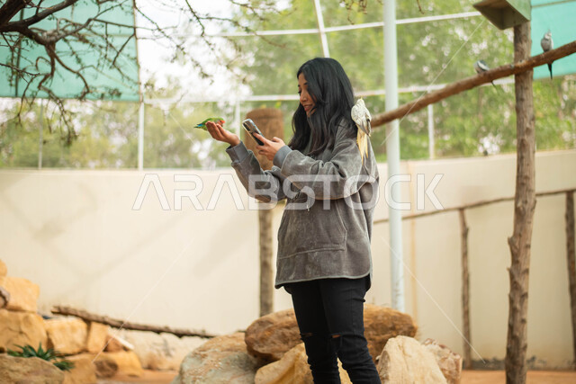 التقاط  صور تذكاريه باستخدام الهاتف المحمول، فتاة عربية خليجية سعودية تقضي أوقات ممتعة في حديقة الحيوانات في المملكة العربية السعودية، موهبة التصوير، أماكن سياحية ترفيهية، حيوانات برية في المحمية الطبيعية، فعالية سفاري موسم الرياض