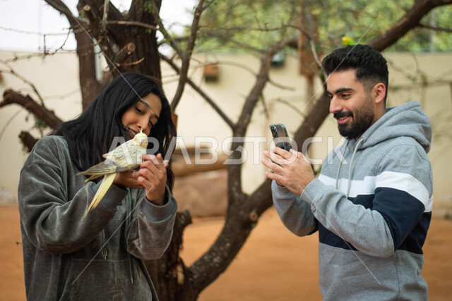  قضاء أوقات ممتعة عائلية في موسم سفاري الرياض، توثيق اللحظات بالتقاط صور تذكارية مع الحيوانات البرية في المحمية الطبيعية، زوجان عربيان خليجيان سعوديان يقومان بجولة في حديقة الحيوان في المملكة العربية السعودية