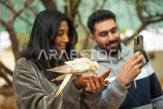 ايماءات تدل على السعادة، أنشطة ترفيهية، زوجان عربيان خليجيان سعوديان في محمية الطيور في حديقة الحيوانات في السعودية ، استخدام الهاتف المحمول، التقاط  صور تذكارية، فعالية سفاري موسم الرياض.