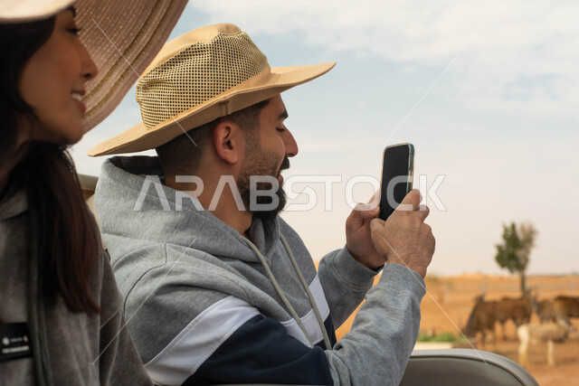 التقاط صور تذكارية لتوثيق اللحظات الجميلة,  زوجان عربيان خليجيان سعوديان يقومان بجولة سياحية في حديقة الحيوانات في المملكة العربية السعودية, ايماءات وجه تدل على السعادة و الاستمتاع, أوقات ممتعة و فعاليات ترفيهية عائلية في سفاري الرياض.
