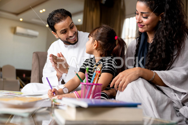 تلميذة سعودية خليجية تدرس في المنزل مع والدها و والدتها ، يساعدانها على تأدية واجباتها المدرسية ، التعلم عن بعد ، مفهوم التعليم عبر الانترنت ، التعليم المنزلي اثناء الحجر الصحي و تفشي فيروس كورونا ، العزلة الذاتية .