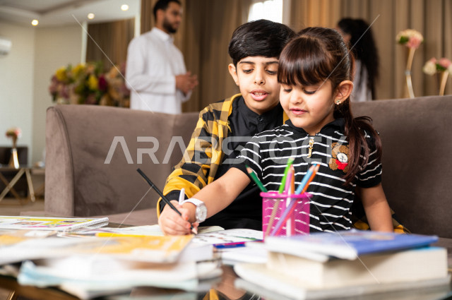 اخ و اخت سعوديان خليجيان يدرسان في المنزل و يؤديان واجباتهم المدرسية ، التعلم عن بعد ، مفهوم التعليم عبر الانترنت ، التعليم المنزلي اثناء الحجر الصحي و تفشي فيروس كورونا ، العزلة الذاتية .