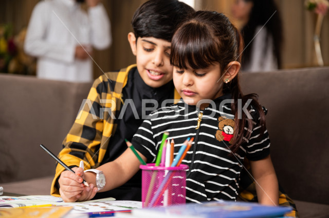 اخ و اخت سعوديان خليجيان يدرسان في المنزل و يؤديان واجباتهم المدرسية ، التعلم عن بعد ، مفهوم التعليم عبر الانترنت ، التعليم المنزلي اثناء الحجر الصحي و تفشي فيروس كورونا ، العزلة الذاتية .