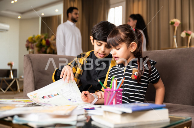 اخ و اخت سعوديان خليجيان يدرسان في المنزل و يؤديان واجباتهم المدرسية ، التعلم عن بعد ، مفهوم التعليم عبر الانترنت ، التعليم المنزلي اثناء الحجر الصحي و تفشي فيروس كورونا ، العزلة الذاتية .