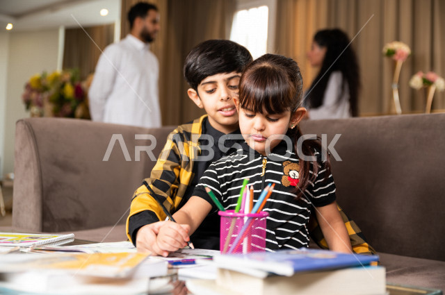 اخ و اخت سعوديان خليجيان يدرسان في المنزل و يؤديان واجباتهم المدرسية ، التعلم عن بعد ، مفهوم التعليم عبر الانترنت ، التعليم المنزلي اثناء الحجر الصحي و تفشي فيروس كورونا ، العزلة الذاتية .