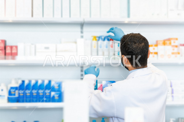 A Saudi Gulf pharmacist working in the pharmacy, checking and verifying the stock of medicines, medicines and medical supplies, the profession of pharmacy