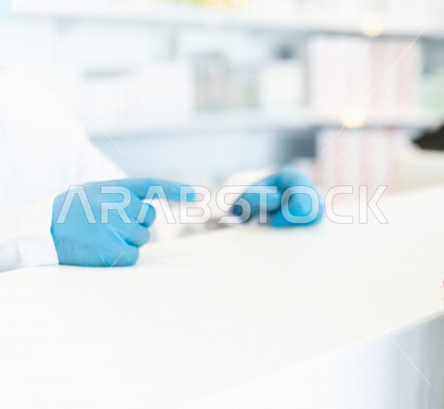 رجل صيدلاني سعودي خليجي يعمل في الصيدلية ، يقوم بتحضير الادوية المناسبة للوصفة الطبية ، خدمات صحية ، تقديم الرعاية الصحية