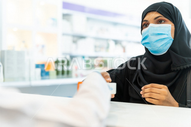 سيدة عربية خليجية سعودية ترتدي الكمامة الطبية للوقاية من فايروس كورونا ، اختيار الادوية والمنتجات الطبية ،شراء الادوية الموجودة في الوصفات الطبية  ، الاستفادة من الخدمات والرعاية الصحية 