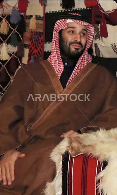 صاحب السمو الملكي ولي العهد الأمير محمد بن سلمان بن عبدالعزيز ال سعود  بإيماءات وجه تدل على الإبتسامة,  ارتداء العباءة و الزي السعودي التقليدي, جلسات شعبية في المملكة العربية السعودية .