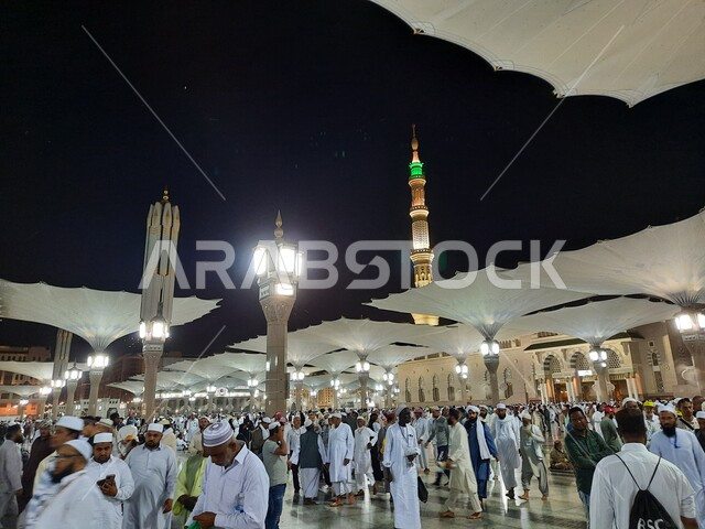 تجول المصلين ليلا في المجمع الخارجي للمسجد النبوي في المدينة المنورة، المظلات الالكترونية في ساحة المسجد النبوي الشريف في المدينة المنورة في المملكة العربية السعودية، معالم دينية إسلامية, العبادة والتقرب الى الله، الحرم النبوي الشريف، أماكن إسلامية مقدسة
