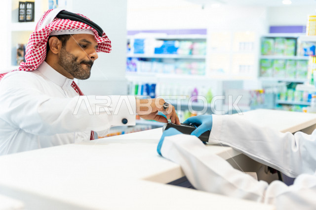 رجل عربي خليجي سعودي داخل الصيدلية ، يقوم بدفع ثمن الادوية من خلال البطاقة الائتمانية ، شراء الادوية والمستلزمات الطبية ،طلب الادوية الموجودة في الوصفة الطبية ، الاستفادة من الخدمات الصحية