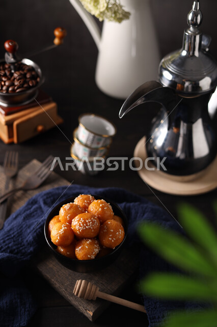 دلة قهوه عربية مع طبق من الحلويات اللذيذ ، طبق لقيمات شهية ، الضيافة الرمضانية ،حلويات و سكريات,  مطاعم للمأكولات العربية الشرقية, خلفية سوداء