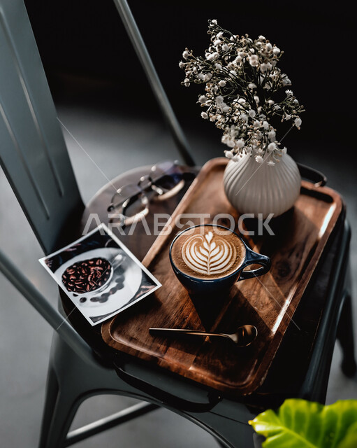 ديكورات وزينة و أجواء هادئة, كوب من القهوه برغوة كثيفة مع رسومات على قاعدة خشبية على الكرسي ، مشروبات ساخنة لذيذة ، مشروب الكابتشينو الساخن ، قهوة اسبرسو, كافيهات ومطاعم في السعودية