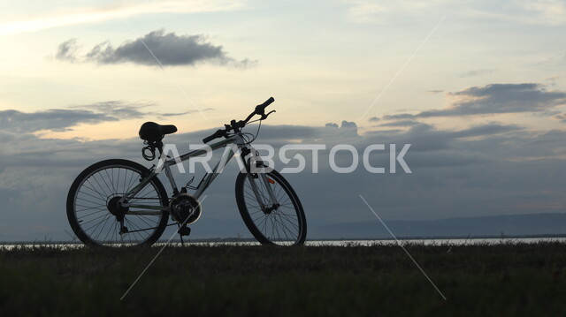 A view of the sky full of clouds, a bicycle on the lake at sunset in the Kingdom of Saudi Arabia, tourist places, nature background, cellulite.