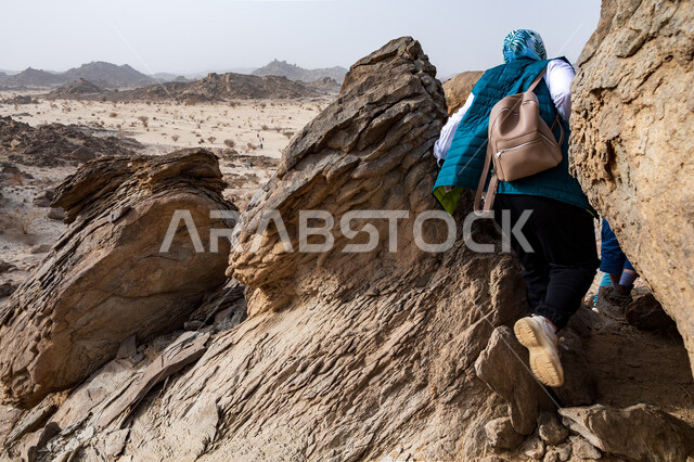 A group of Saudi Arab Gulf youth climbing mountains, walking in the desert, the Moon Mountains in the city of Jeddah in the Kingdom of Saudi Arabia, practicing hiking, mountain peaks and heights, mountain stones and rocks, tourist places in Saudi Arabia, 