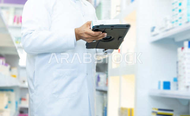 A man is a Saudi Arabian Gulf pharmacist who makes an inventory of medicines inside the pharmacy, checking the stock of medicines and taking notes on the portfolio, providing high-quality health care, medicines and medical supplies, the pharmacy professio