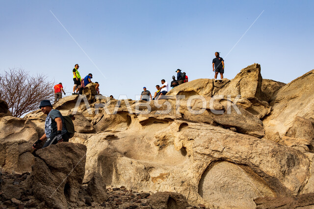 ممارسة رياضة الهايكنج، مجموعة من الشباب العرب الخليجيين السعوديين يتسلقون الجبال، المشي في الصحراء، جبال القمر في مدينة جدة في المملكة العربية السعودية، قمم ومرتفعات جبلية، حجارة وصخور جبلية، اماكن سياحية في السعودية، انشطة بدنية ترفيهية