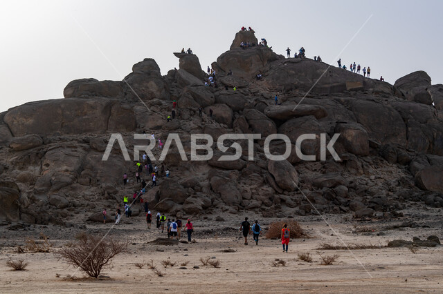 Walking in the desert, a group of Saudi Gulf Arab youth climbing mountains, the Moon Mountains in the city of Jeddah in the Kingdom of Saudi Arabia, hiking, mountain peaks and heights, mountain stones and rocks, tourist places in Saudi Arabia, recreationa