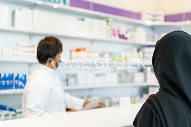  سيدة عربية خليجية سعودية تقوم بتقديم الوصفة الطبية لصيدلي خليجي سعودي ، ارتداء الكمامة الطبية للوقاية من فايروس كورونا ،صرف الادوية الموجودة في الوصفات الطبية ، توفير وتجهيز الادوية اللازمة للمريضة ، بيع الادوية والمستلزمات الطبية ، مهنة الصيدلة