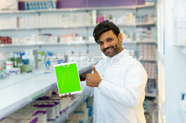 صيدلي عربي خليجي سعودية يحمل بيده جهاز التابلت بشاشة كروما الخضراء  ، عرض الادوية والمنتجات الطبية ، بيع الادوية اونلاين ، الاعلان والتسويق للمستلزمات الطبية ، مهنة الصيدلة 